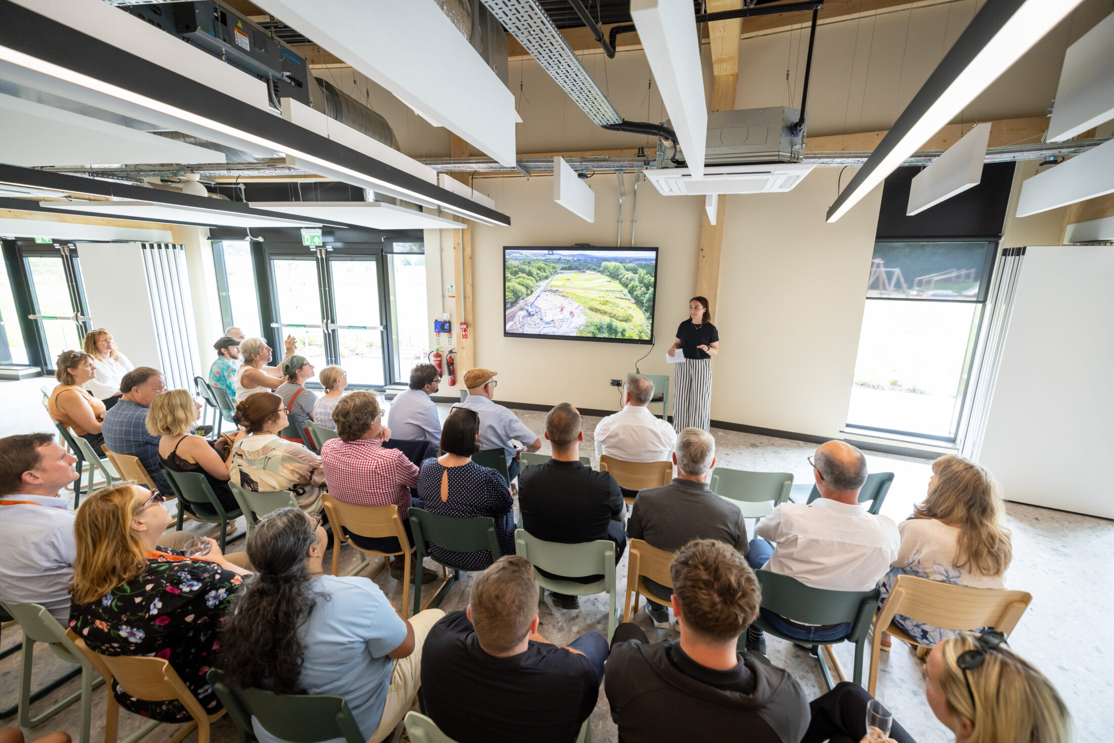 People sit in rows in front of a screen while a member of the Northern Roots team presents our work. Credit: Darren Robinson Photography Ltd.