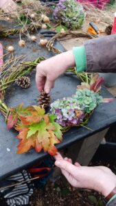 Someone making a seasonal wreath made of natural materials.