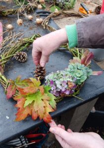 Someone making a seasonal wreath made of natural materials.